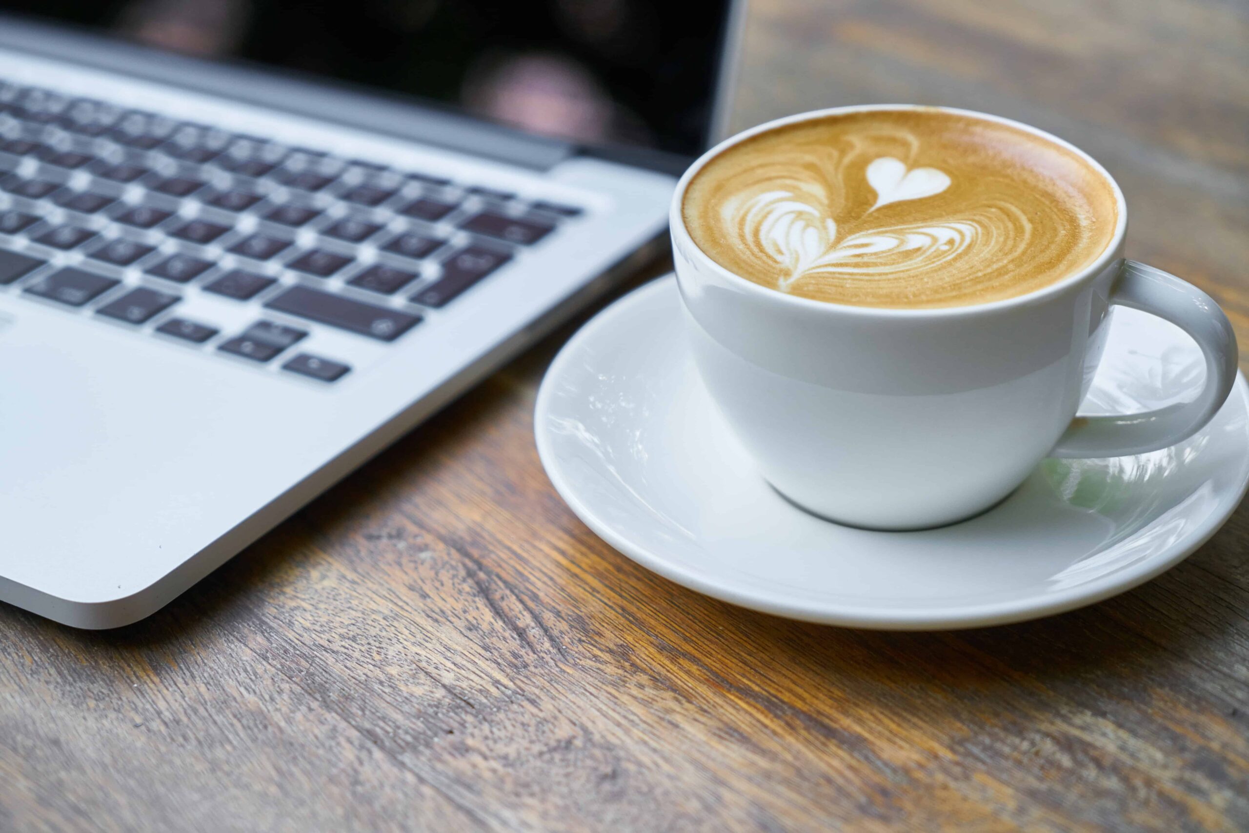 Cup of coffee next to laptop