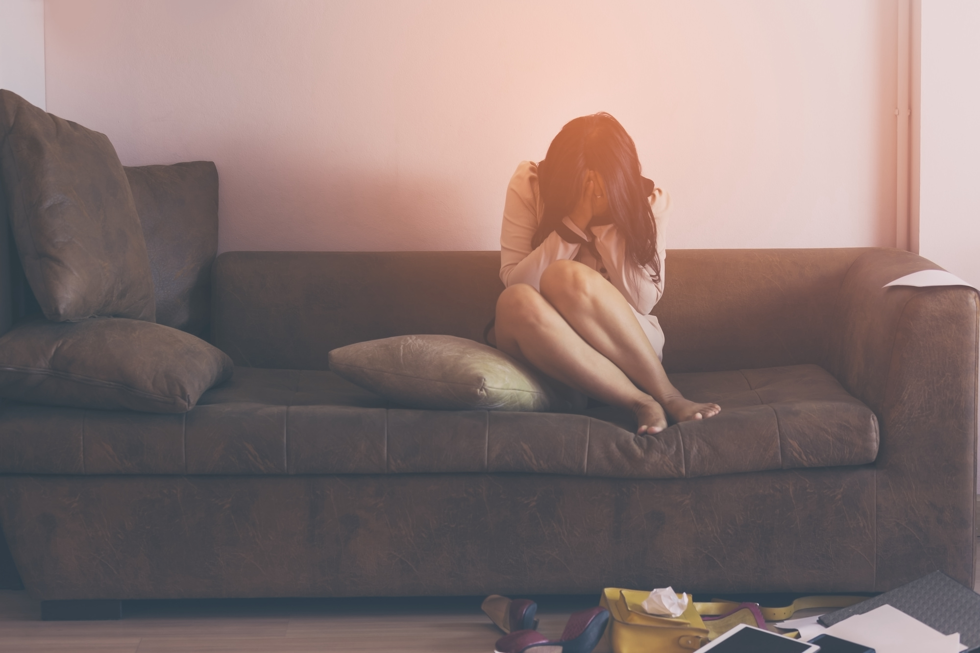 woman seated on couch with hands covering her face